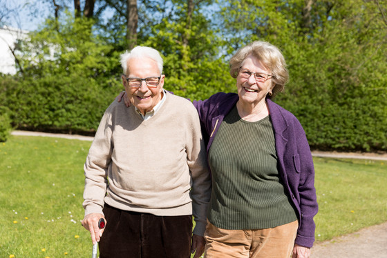 Ein Senior und eine Seniorin machen Arm in Arm einen Spaziergang an der frischen Luft, Pflege in gewohnter Umgebung, Pflegeunterstützung zu Hause, pflegende Hilfe im eigenen Haus, Residenz am Wiesenkamp, Hamburg-Volksdorf