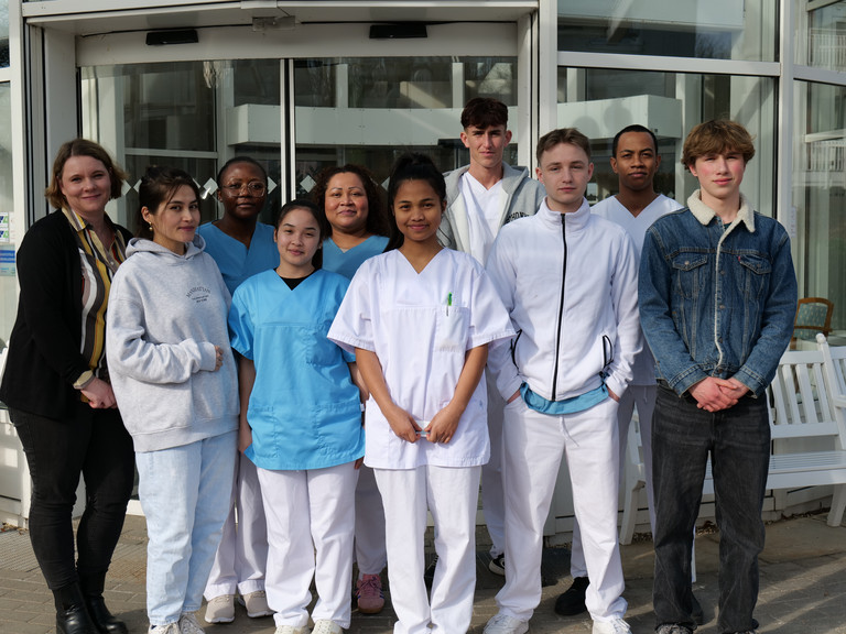 Gruppenfoto mit drei neuen Auszubildenden als Pflegefachfrau bzw. zum Pflegefachmann und drei Auszubildenden als Gesundheits- und Pflegeassistenz vor dem Eingang der Residenz am Wiesenkamp mit Petra Furmanski, hauptamtliche Praxisanleiterin und Ansprechpartnerin für die Auszubildenden.
