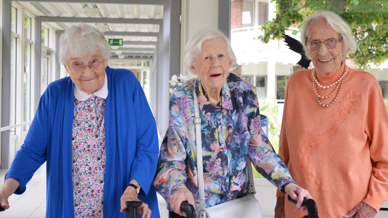 Nora Matthaei (101 Jahre), Hannelore Sieg (99 Jahre) und Else Pahling (101 Jahre) lächeln bei einem gemeinsamen Gruppenfoto vor der Residenz am Wiesenkamp in Hamburg-Volksdorf zu ihren Geburtstagen im Juli in die Kamera