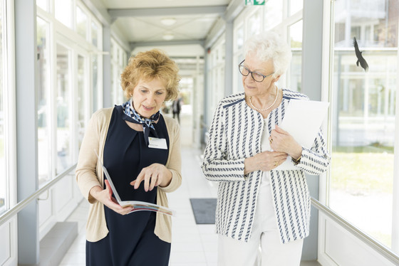 Eine Residenzmitarbeiterin berät eine interessierte Seniorin, Außenansicht, Residenzberatung