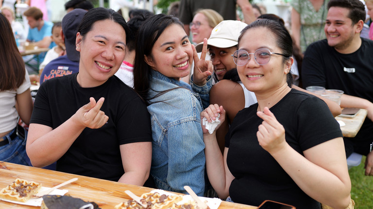 Drei Mitarbeiterinnen sitzen an einem Tisch mit Essenstellern und blicken fröhlich in die Kamera beim Sommerfest 2026 auf dem Gesundheitscampus Volksdorf der Einrichtungen des Evangelischen Amalie Sieveking Krankenhauses, der Residenz am Wiesenkamp, des Feierabendhauses Volksdorf und der Albertinen Kindertagesstätte Volksdorf. Drei Mitarbeiterinnen sitzen an einem Tisch mit Essenstellern und blicken fröhlich in die Kamera beim Sommerfest 2026 auf dem Gesundheitscampus Volksdorf der Einrichtungen des Evangelischen Amalie Sieveking Krankenhauses, der Residenz am Wiesenkamp, des Feierabendhauses Volksdorf und der Albertinen Kindertagesstätte Volksdorf.