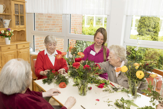 Eine Gruppe Seniorinnen steckt mit einer Pflegekraft Blumensträuße, Pflege in der Residenz, Stationäres Pflegeangebot, Wohnen und pflegerische Unterstützung in Hamburg-Volksdorf, Residenz am Wiesenkamp